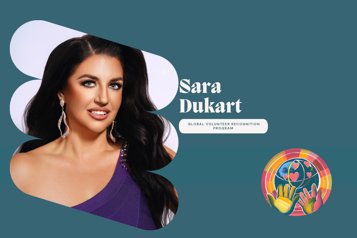 Dr Sara Dukart Woman wearing a purple one-shoulder dress with long dark hair and earrings on a light gray background