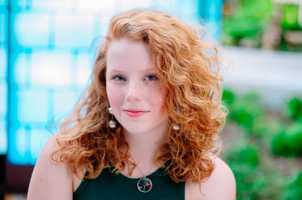 Portrait of Madeleine Smith, a teen leader and aspiring medical star with curly red hair and a confident smile.