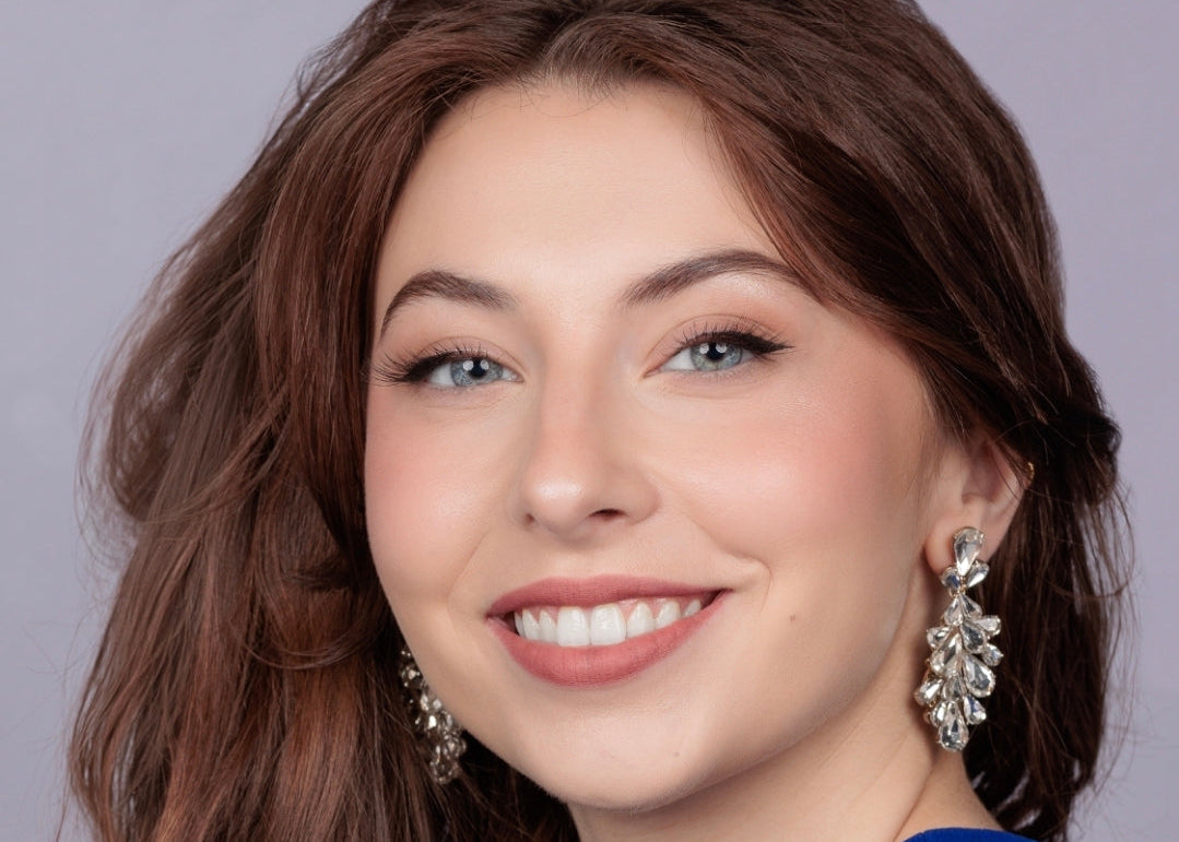 Woman with long brown hair wearing a blue top against a gray background