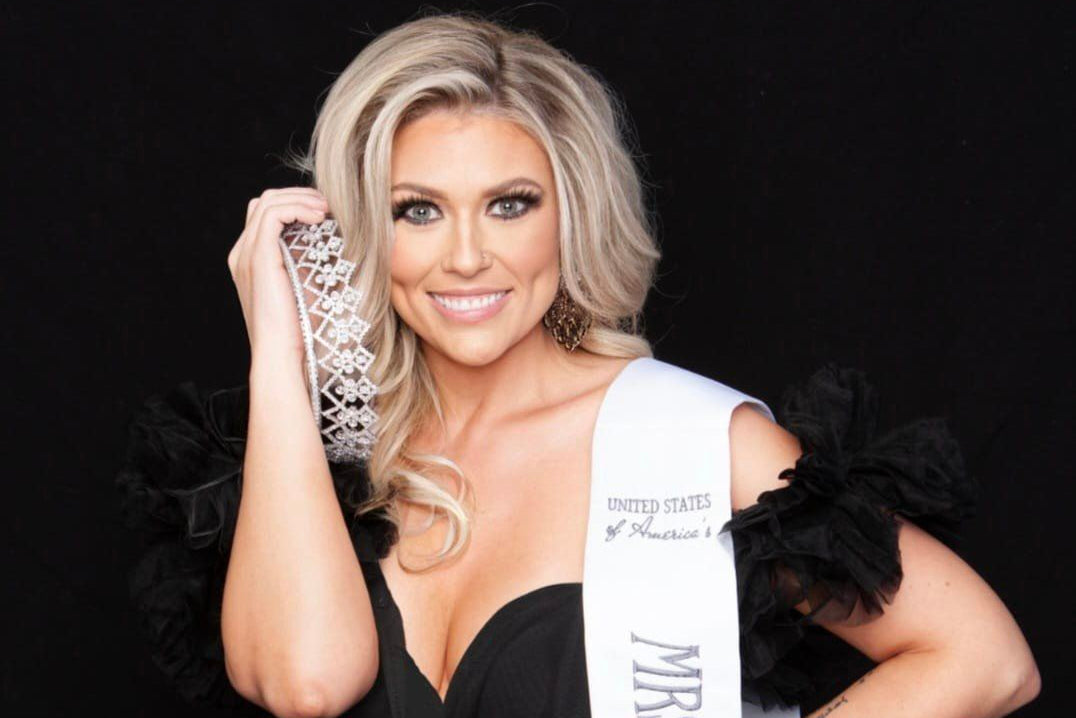 Sara DornBrook Woman wearing a USOA sash holding a crown against a black background