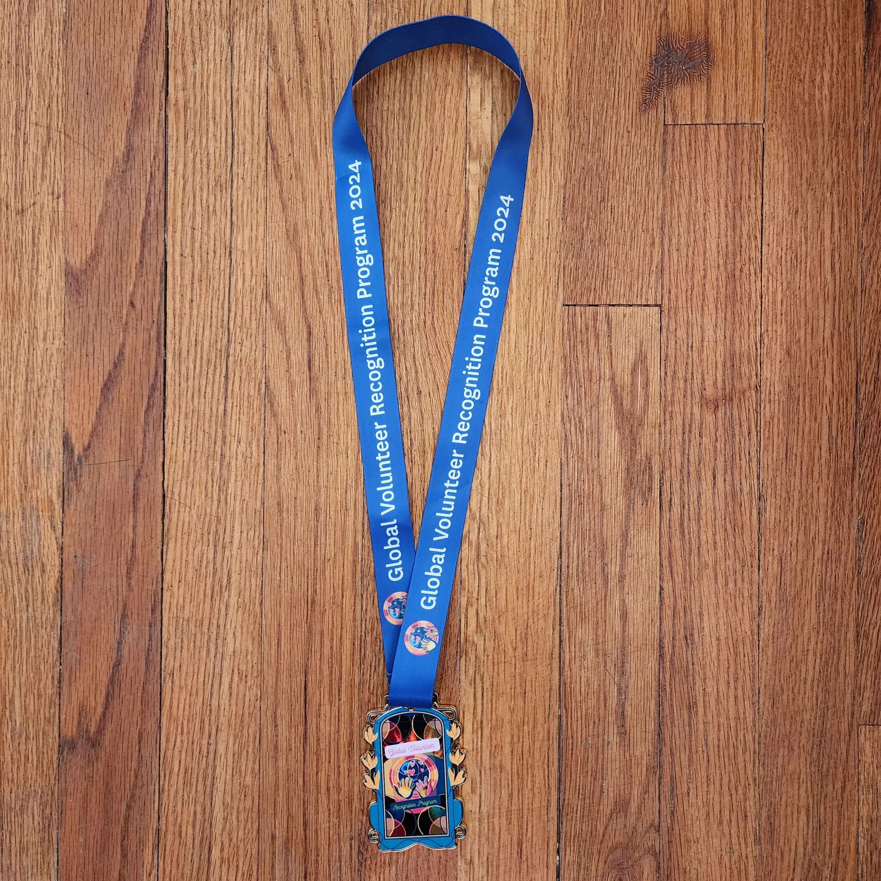 2024 Global Volunteer Recognition Program Membership Blue lanyard with a colorful badge holder 
