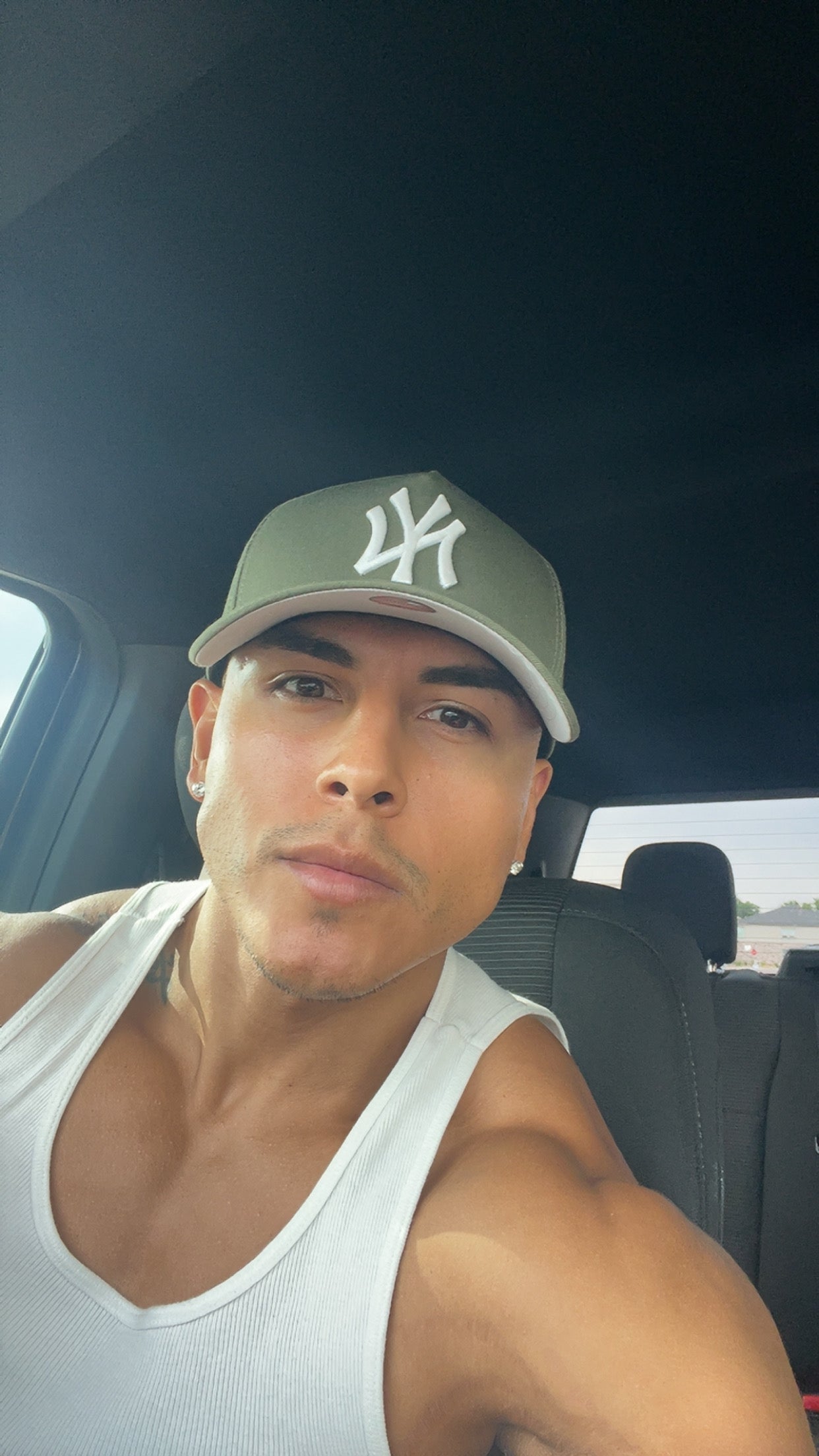 Man wearing a green cap with a logo inside a vehicle