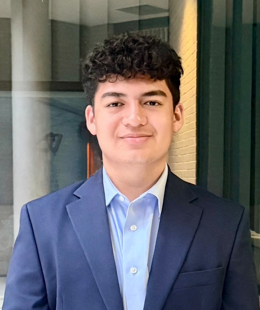 Young man in a blue suit standing in front of a building entrance.