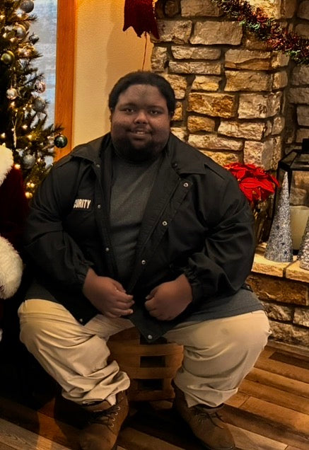 Person sitting in front of a stone fireplace with Christmas decorations