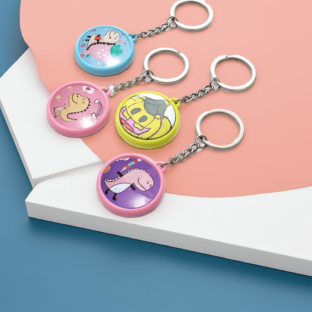 Personalized Four colorful 1 inch custom keychains featuring fun cartoon designs on a modern geometric background.