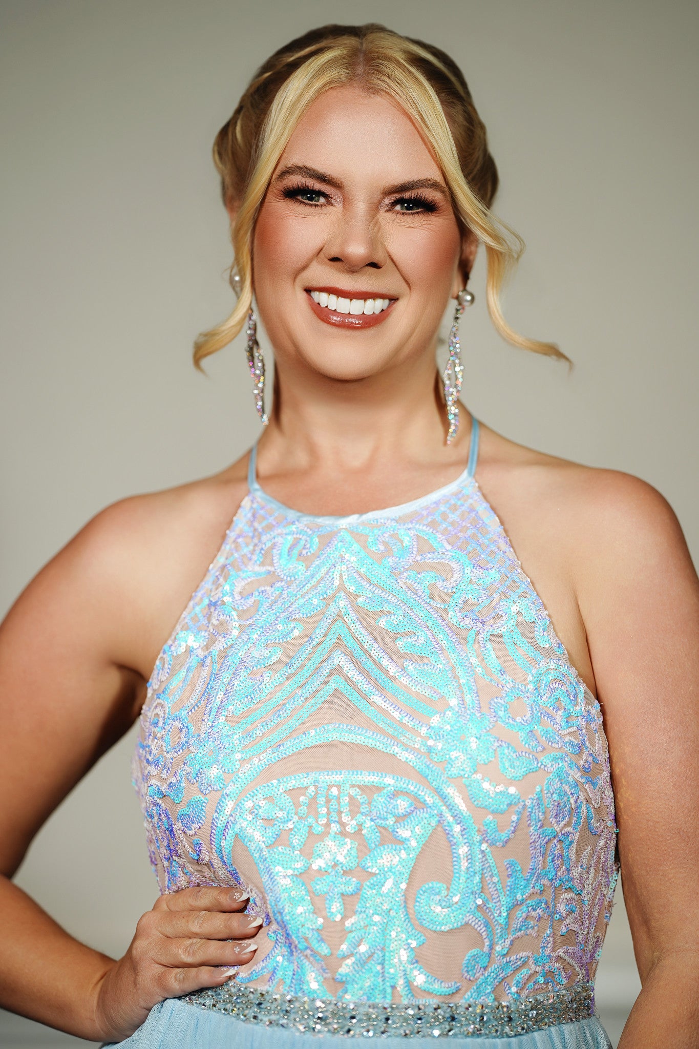 Woman wearing a sparkling blue dress against a neutral background