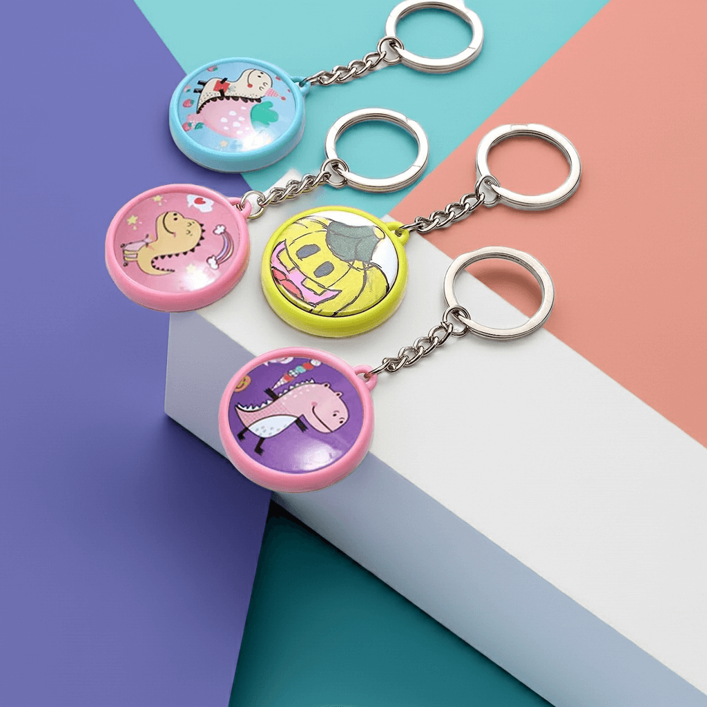 Personalized Four colorful 1 inch custom keychains featuring fun cartoon designs on a modern geometric background.