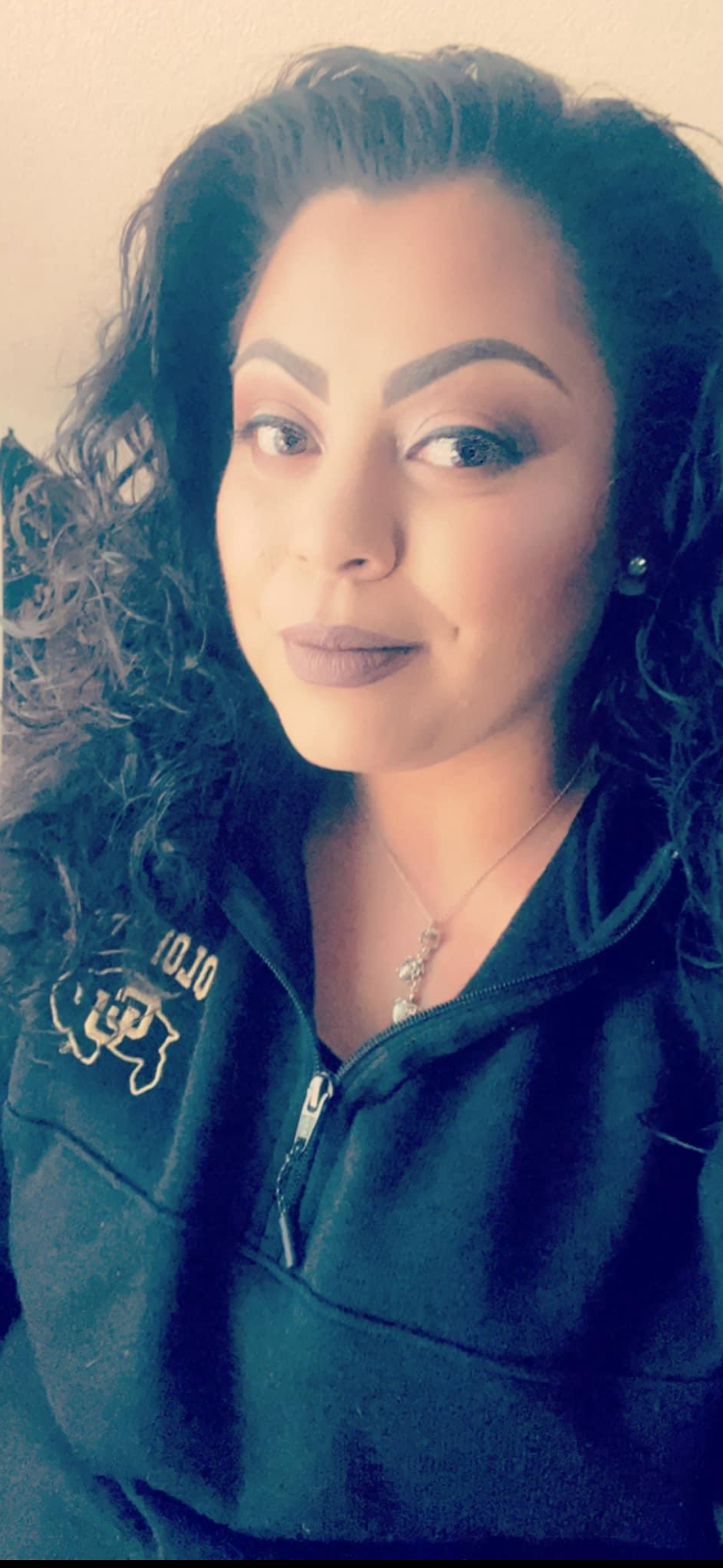 Woman wearing a black jacket with a logo on a beige background