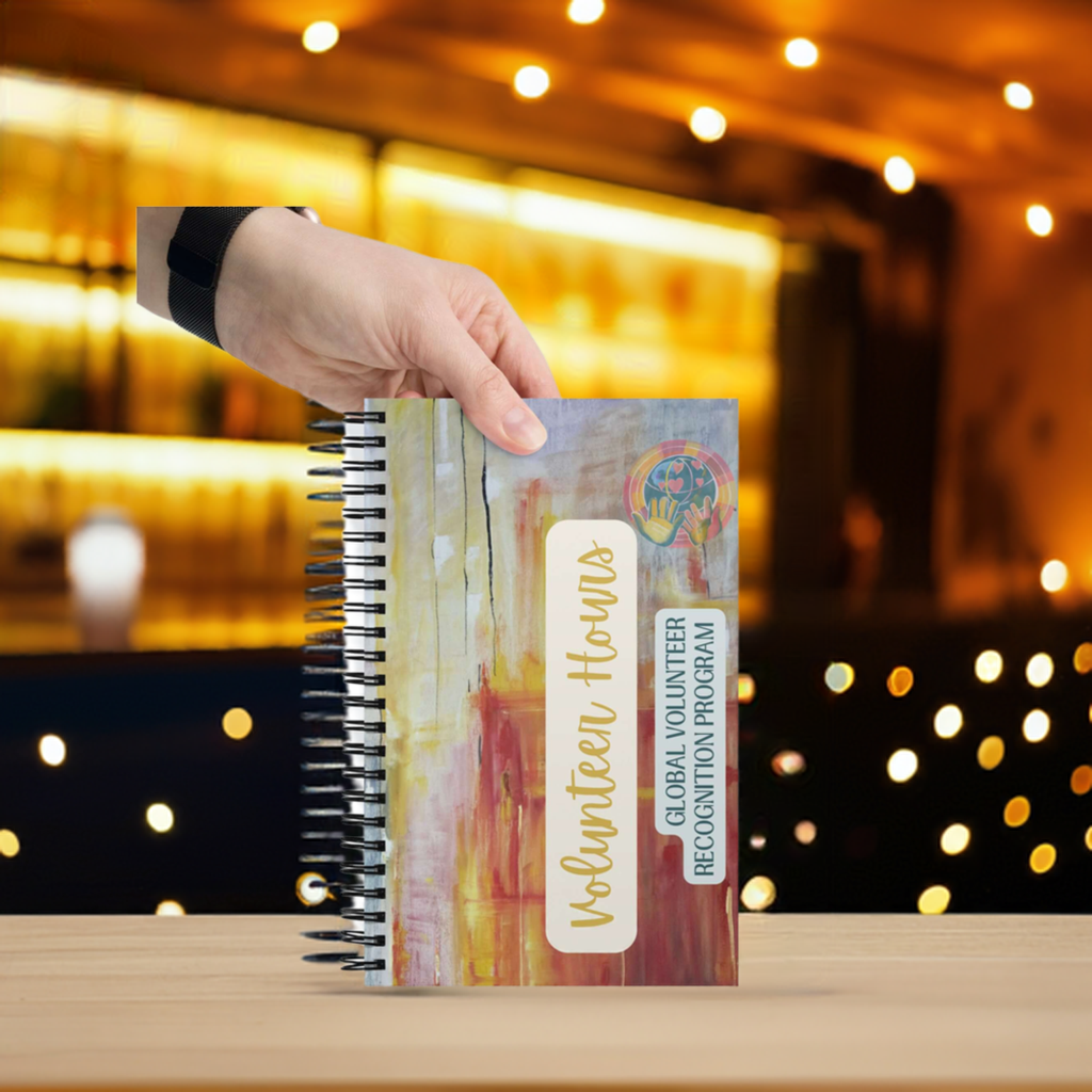 Notebook with 'Volunteer Hours' and 'Global Volunteer Recognition Program' text held by a hand