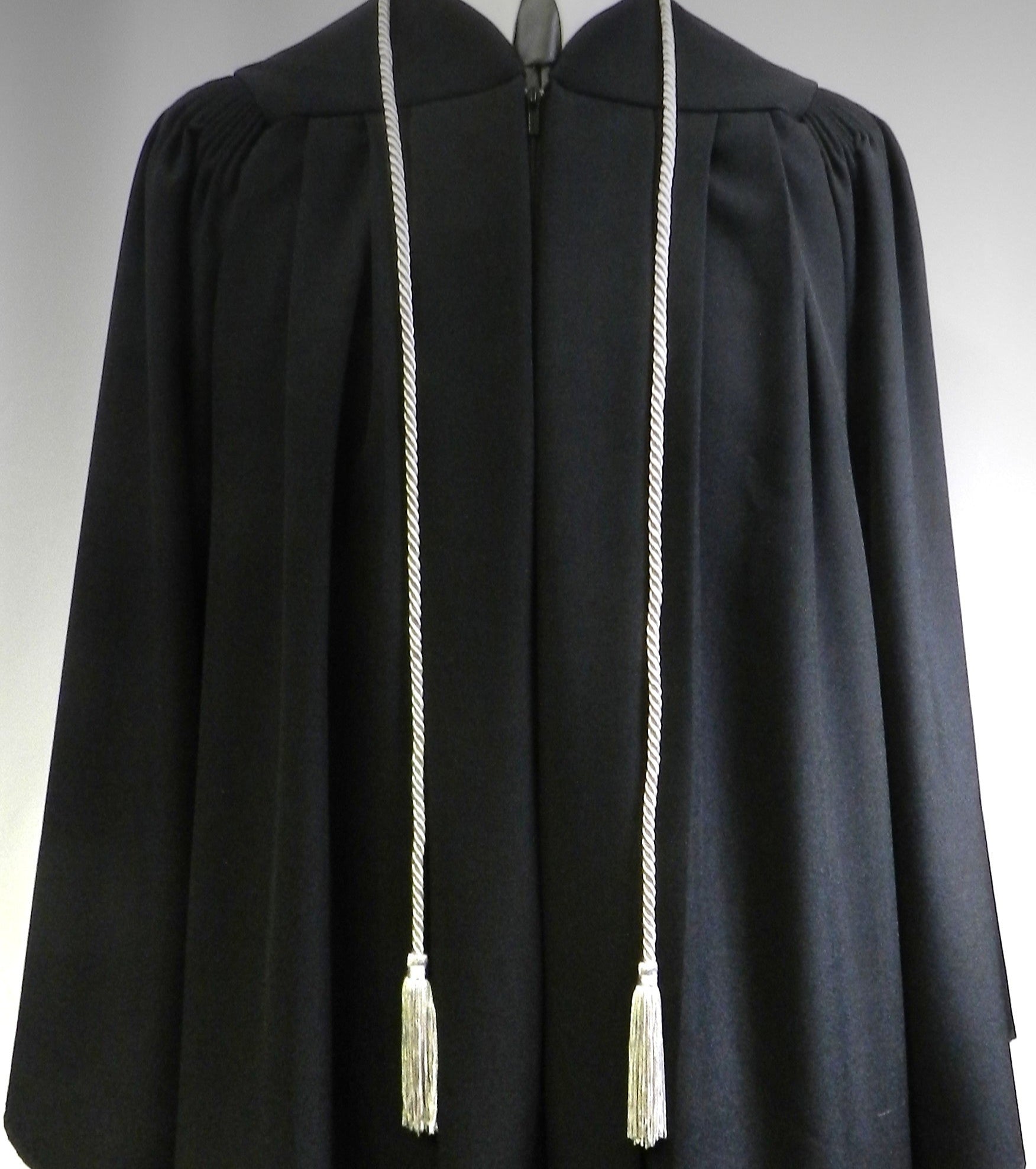 Black academic gown with white tassels on a gray background