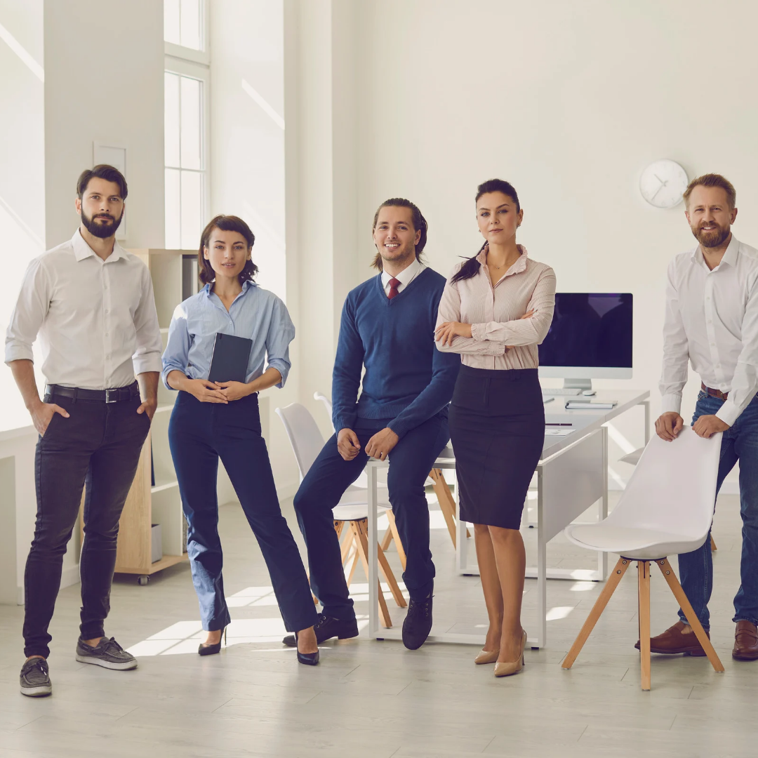 Group of five professionals standing in a modern office setting