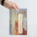 Spiral Notebook with 'Volunteer Hours' and 'Global Volunteer Recognition Program' text held by a hand on a white background